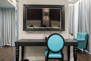 Une pièce moderne avec une table en bois foncé, une chaise bleue et un grand téléviseur à écran plat fixé au mur.