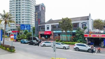 Vista de la calle con un edificio residencial alto, un restaurante KFC y una tienda de conveniencia.