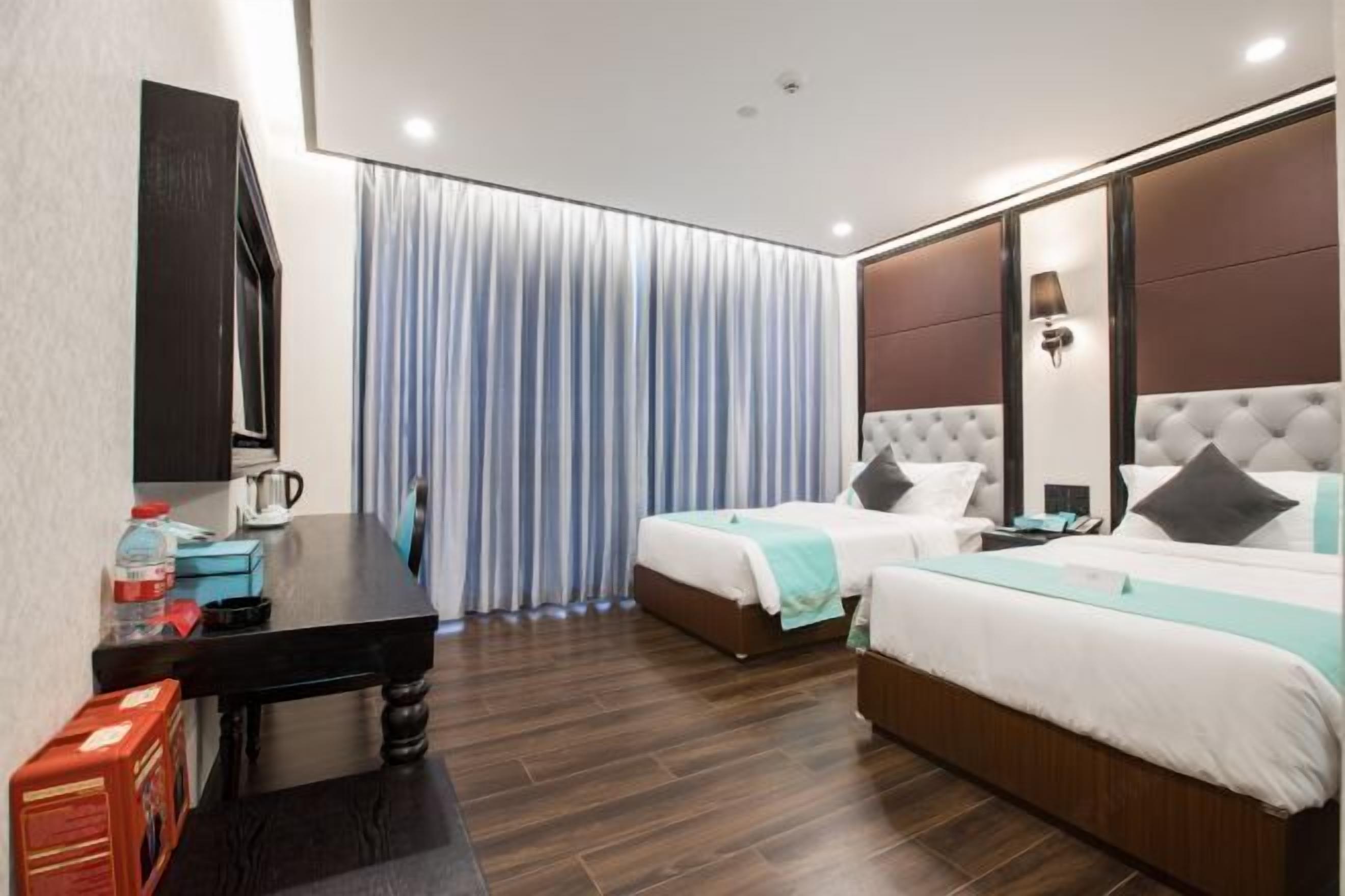 A hotel room with two beds, a desk, a coffee maker, and a TV.