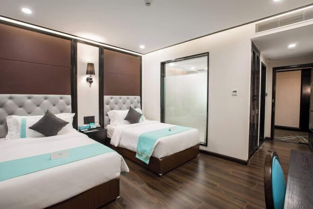 A hotel room with two beds, a nightstand, a desk, and a sliding door.