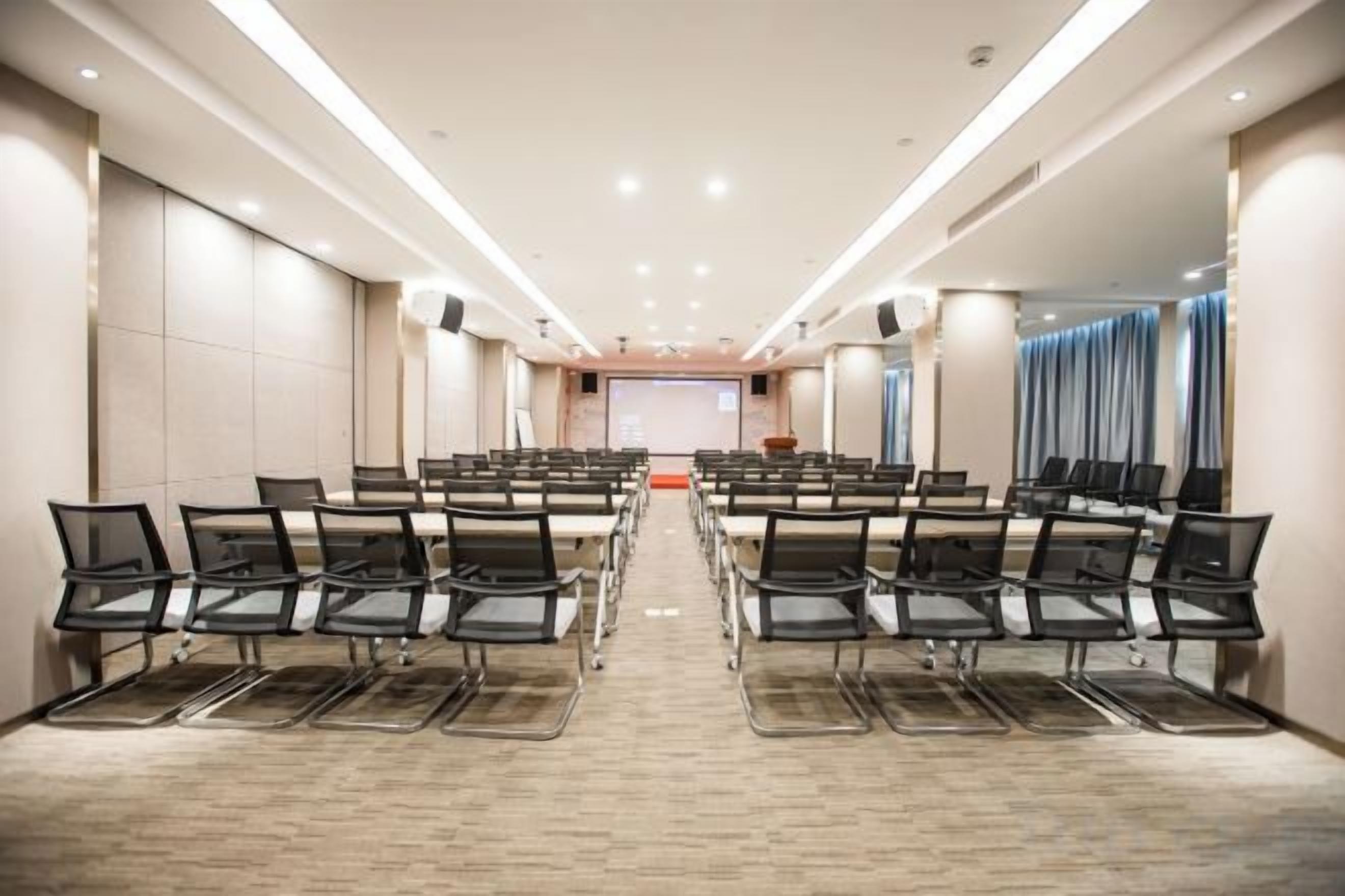 A conference room with rows of chairs, a projector screen, and a presentation area at the front.