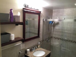 A bathroom with a sink, mirror, and shower. There are toiletries on the shelf. - Inlet View House - Downtown Anchorage (Anchorage)