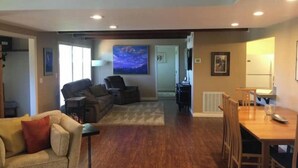 A spacious living area with a sofa, chairs, a dining table, and a large painting on the wall. - Inlet View House - Downtown Anchorage (Anchorage)