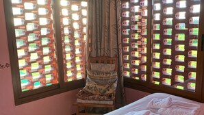 A bedroom with a bed, a chair, and a window with a view of a garden. - EL PAJAR DE ONDINA (Cudillero)
