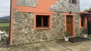 A rustic building with stone walls and a peach-colored facade, featuring a wooden door and a window. - EL PAJAR DE ONDINA (Cudillero)