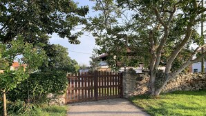 A gravel path leading to a wooden gate, surrounded by greenery and a stone wall. - EL PAJAR DE ONDINA (Cudillero)
