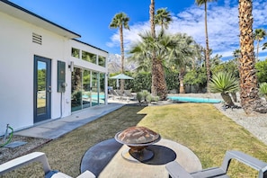 A modern house with a pool, palm trees, and a well-maintained lawn.