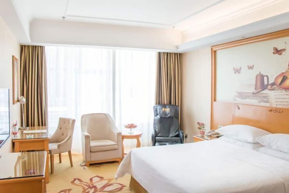 Una habitación de hotel con una cama, dos sillones, un escritorio y una silla.