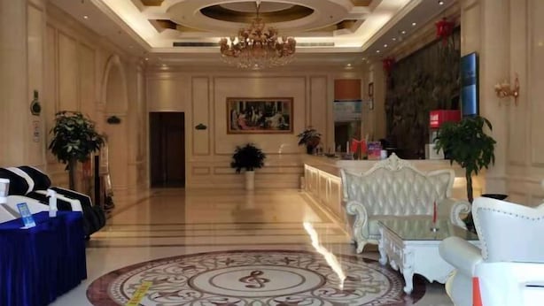 A lobby with a chandelier, a reception desk, a seating area, and a large painting on the wall. - Vienna Hotel (Taihe Chengjiang Avenue) (Taihe)