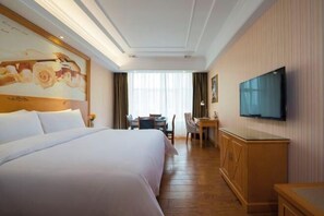 A hotel room with a large bed, a desk, a chair, a television, and a painting on the wall. - Vienna Hotel (Taihe Chengjiang Avenue) (Taihe)