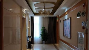 A hotel hallway with a chandelier, a potted plant, and framed artwork on the walls. - Vienna Hotel (Taihe Chengjiang Avenue) (Taihe)