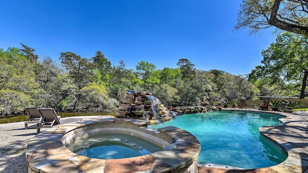 Una piscina con idromassaggio, immersa tra alberi e una cascata.