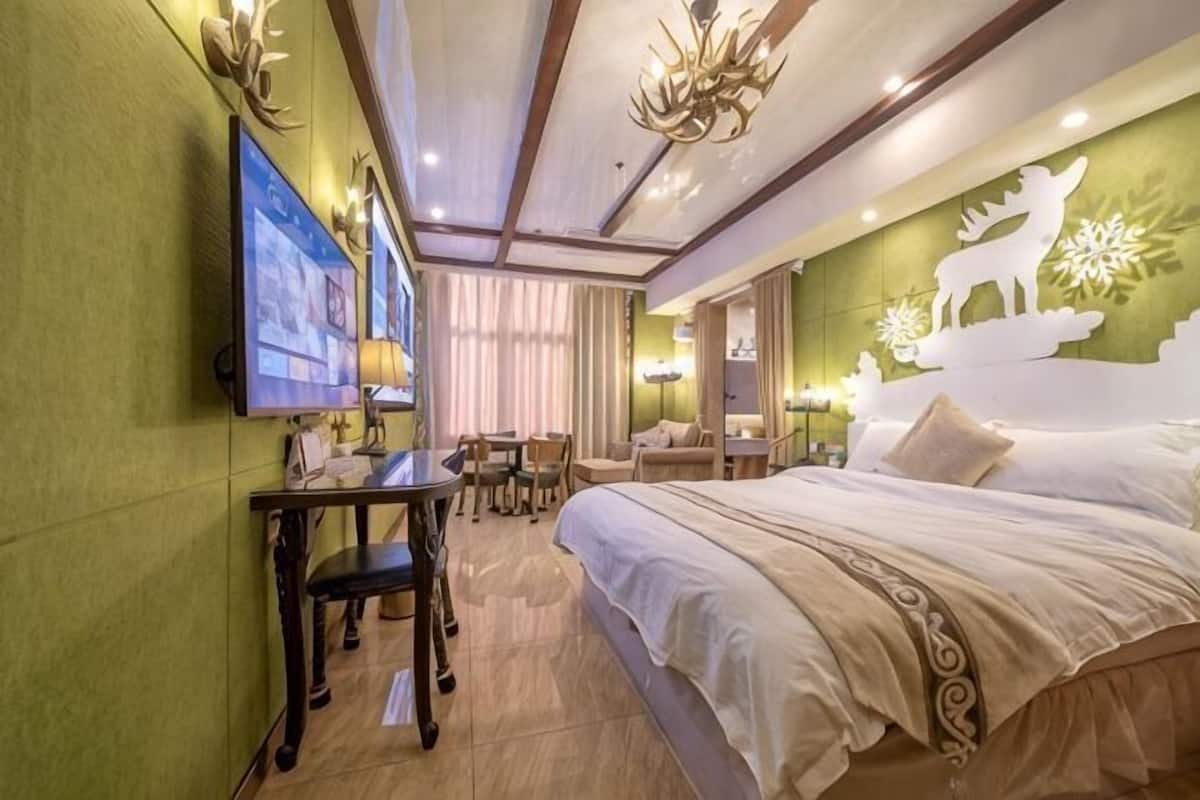 A hotel room with a bed, a desk, a chair, a television, and a chandelier.