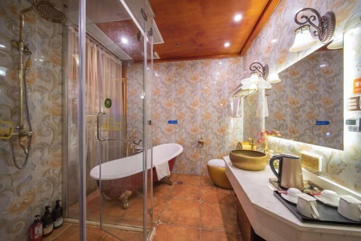 Une salle de bain dotée d’une douche à parois de verre, d’une baignoire de style rétro et d’un meuble-lavabo avec un miroir.