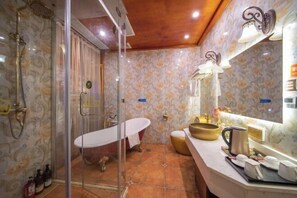 Une salle de bain dotée d’une douche à parois de verre, d’une baignoire de style rétro et d’un meuble-lavabo avec un miroir.