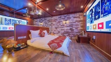 Een moderne hotelkamer met een bakstenen muur, een houten plafond en een groot bed met een rode plaid.