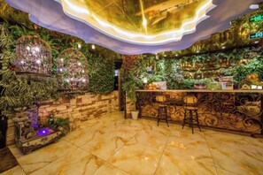 Un espace bar avec un mur en pierre, des plantes vertes et un sol en marbre.