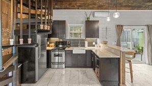 Una cocina moderna con armarios oscuros, electrodomésticos de acero inoxidable y techo de madera.