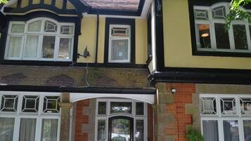 Une maison à deux étages, de style traditionnel, avec une entrée imposante dotée d’une porte noire et d’une grande fenêtre située juste au-dessus.