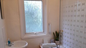 Ein Badezimmer mit Fenster, Waschbecken, Badewanne und Dusche.