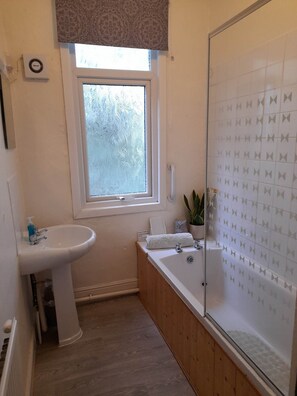 Un baño con ventana, lavabo, bañera y ducha.