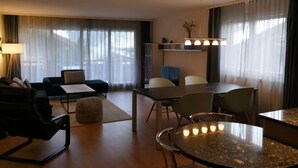 Une chambre d’hôtel moderne comprenant un coin salon, une table à manger et un coin cuisine.