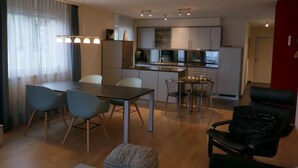 Un salon moderne comprenant un coin repas, une cuisine et un mur d’accent de couleur rouge.