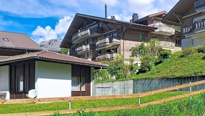 Un immeuble résidentiel doté de nombreux balcons, d’un toit en pente et offrant une vue sur les montagnes en arrière-plan.
