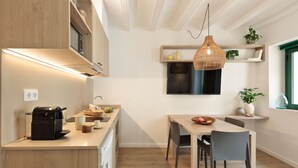 Cozinha moderna com armários de madeira, forno embutido e área de jantar com mesa e cadeiras.