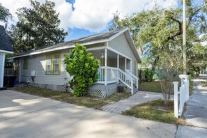 A single-story house with a front porch, a small front yard, and a white picket fence.