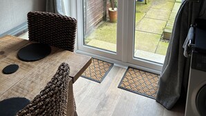 Ein Zimmer mit einem Holztisch, einem Korbstuhl und einer Schiebetür zu einem Garten.
