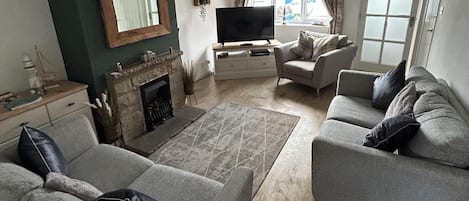 A living room with a fireplace, sofa, armchair, and a television.