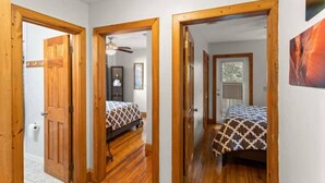 Un corridoio con porte in legno che conduce a una camera da letto con un letto e una ventola a soffitto.