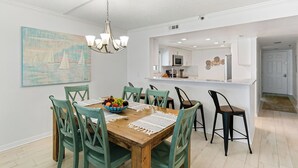 Comedor con mesa de madera, sillas verdes y una lámpara de araña.