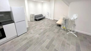 Une cuisine moderne dotée d’un réfrigérateur encastré, d’un canapé gris et d’un ventilateur dans le salon.