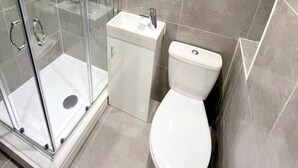 Une salle de bain moderne avec une douche à parois de verre, un lavabo blanc et des toilettes.