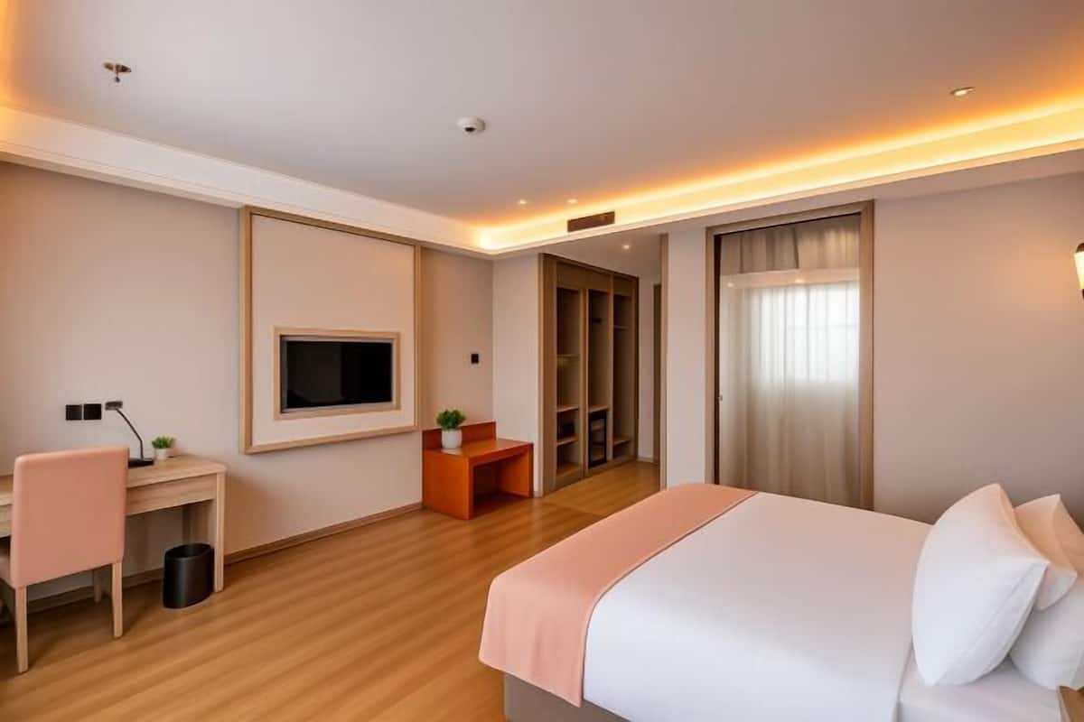 A hotel room with a bed, desk, chair, TV, and closet.