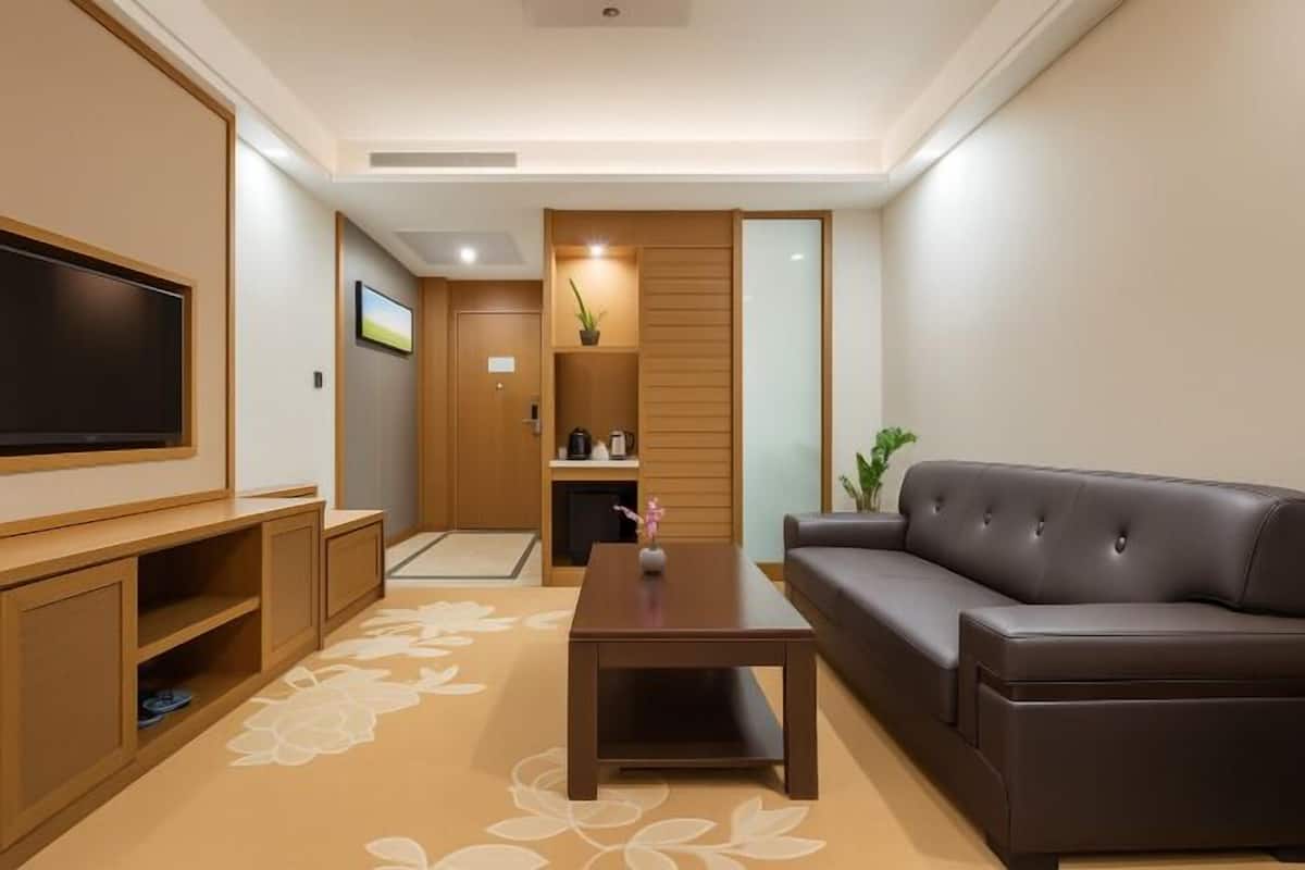 A modern living room with a flat-screen TV, a brown leather sofa, and a wooden entertainment unit.