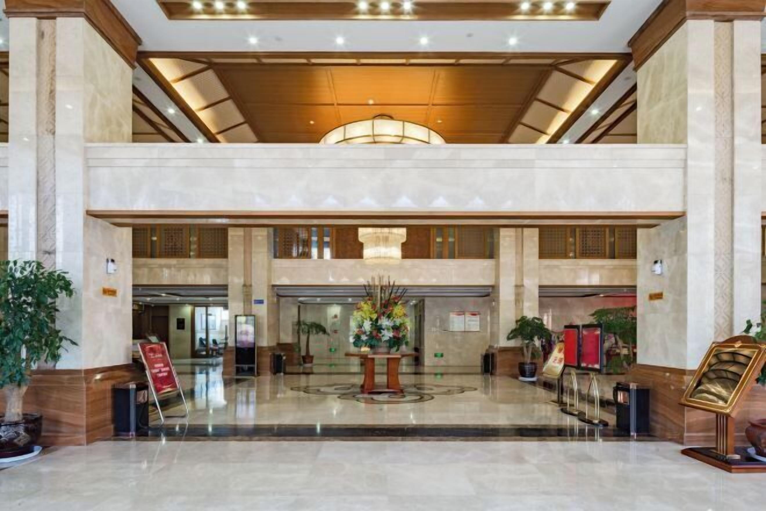A spacious lobby with a high ceiling, a central floral arrangement, and a reception desk.