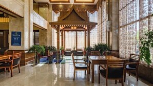 A spacious lobby with a central seating area, a decorative wooden gazebo, and large windows with patterned curtains. - Yunqi Hotel (Kunming)