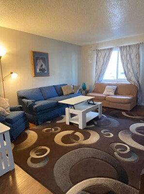 Relax in this stylish living room with a blue sofa, white coffee table, and framed artwork.