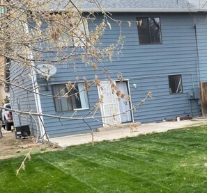 A charming home with a front door and window, set amidst a well-manicured lawn and a tree.