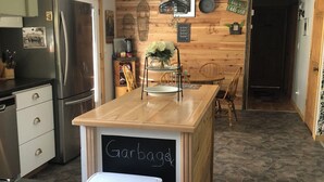 A kitchen with a central island, a refrigerator, a sink, and a chalkboard labeled 'Garbage'.