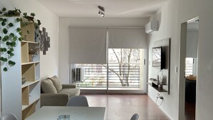 Una sala de estar moderna con comedor, ventanas amplias y un televisor de pantalla plana montado en la pared.