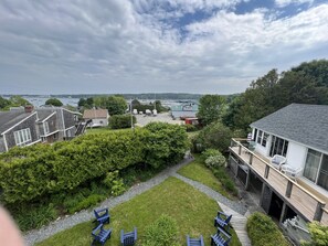 Ein Wohngebiet mit Rasenfläche, einer Holzterrasse und Blick auf eine Marina mit Booten.