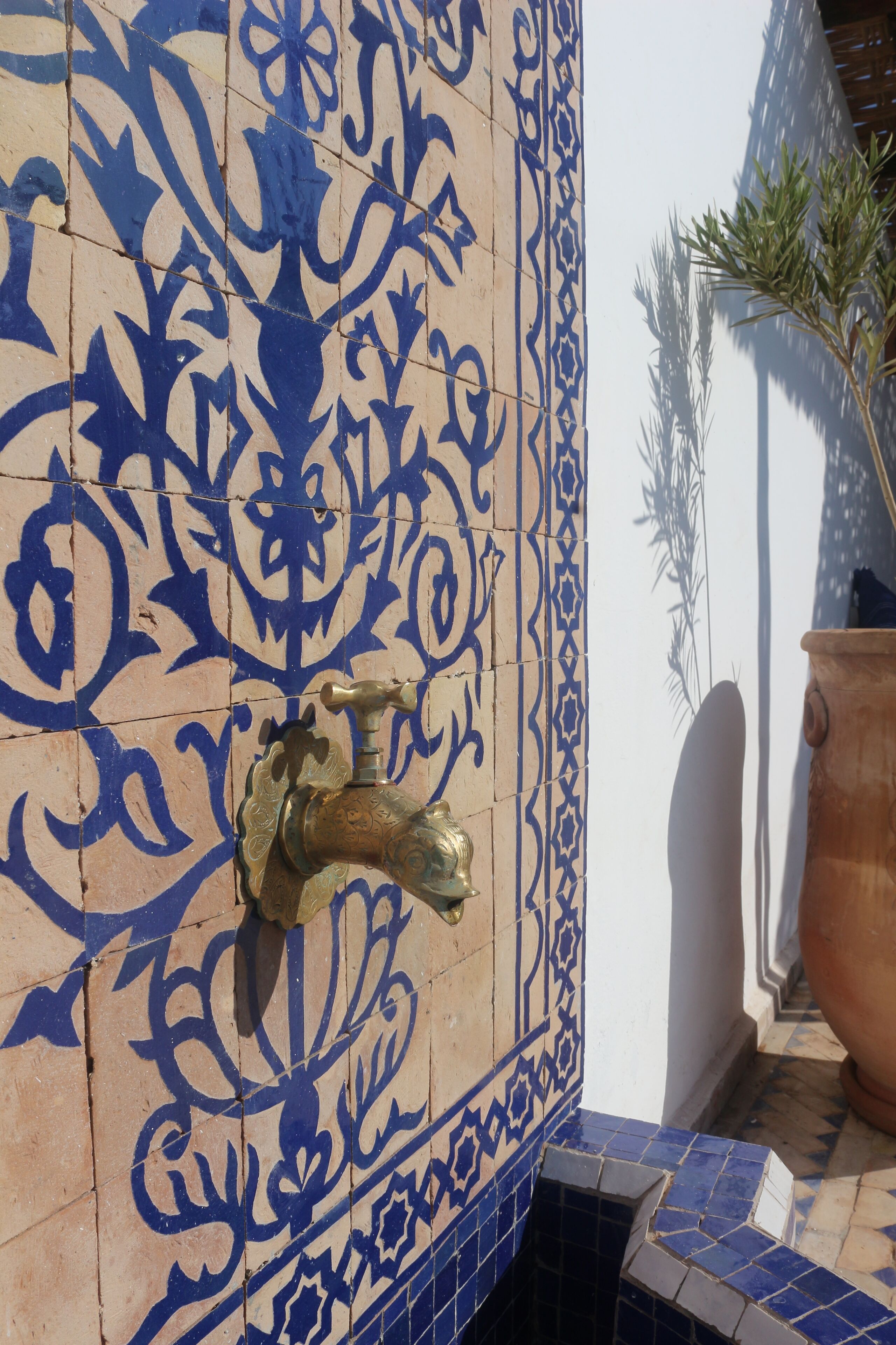 A tiled wall with intricate blue patterns and a brass tap.