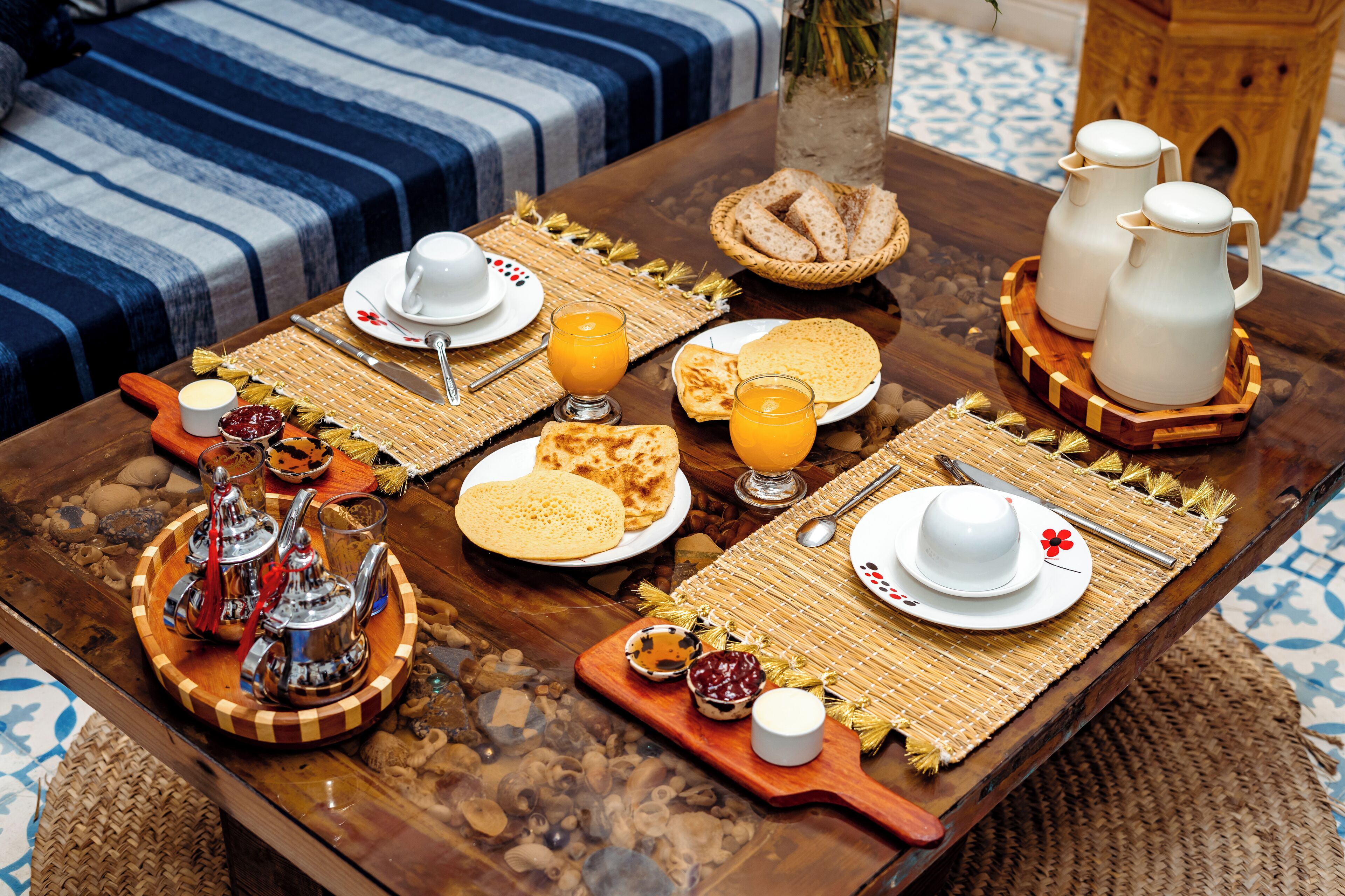 Una mesa de desayuno con platos, vasos y una jarra.