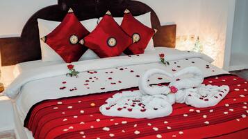 Un lit bien fait, avec une literie rouge et blanche, une tête de lit en bois et des coussins décoratifs.