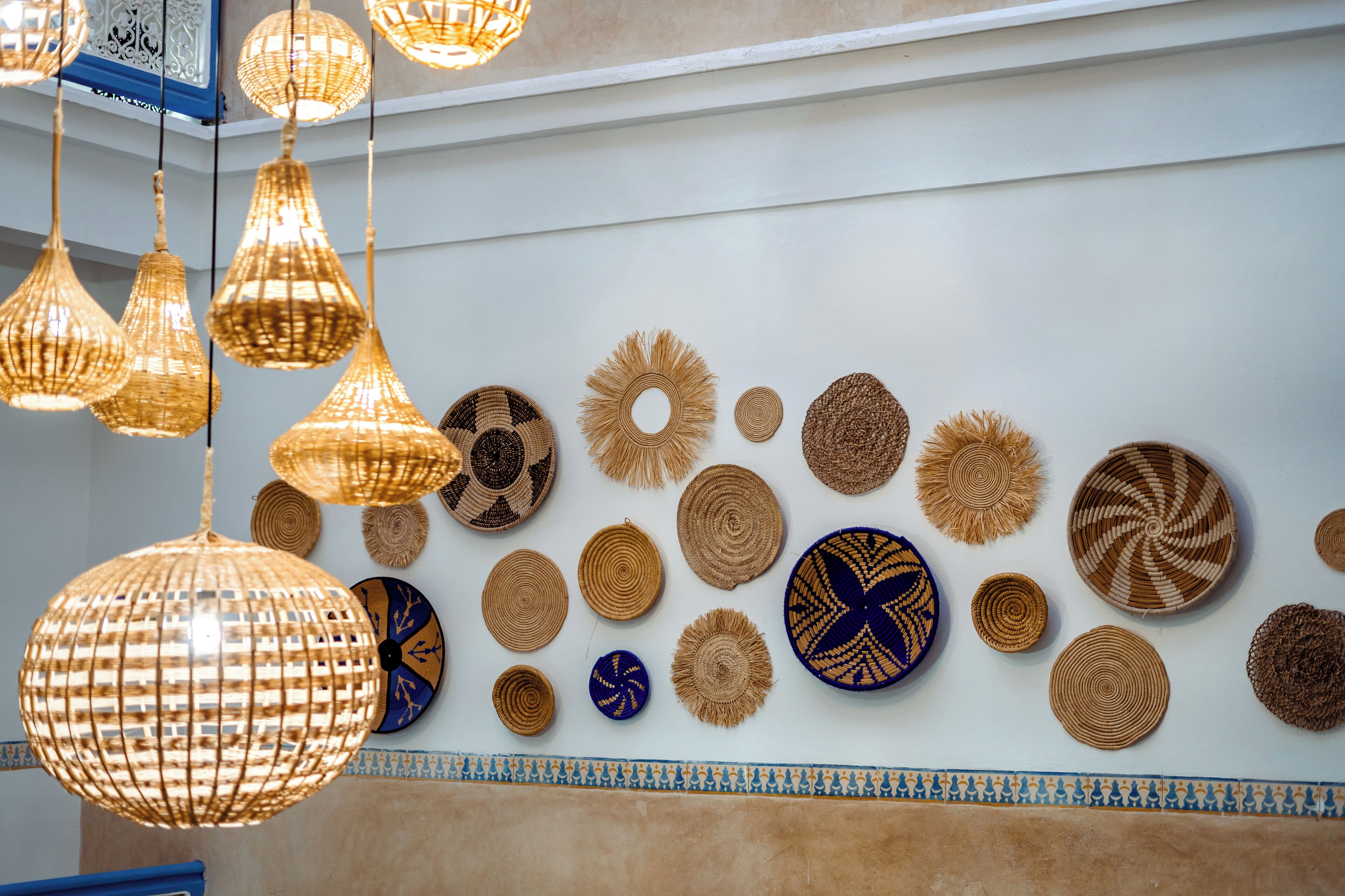 Un mur orné de différents paniers tressés et de luminaires suspendus.