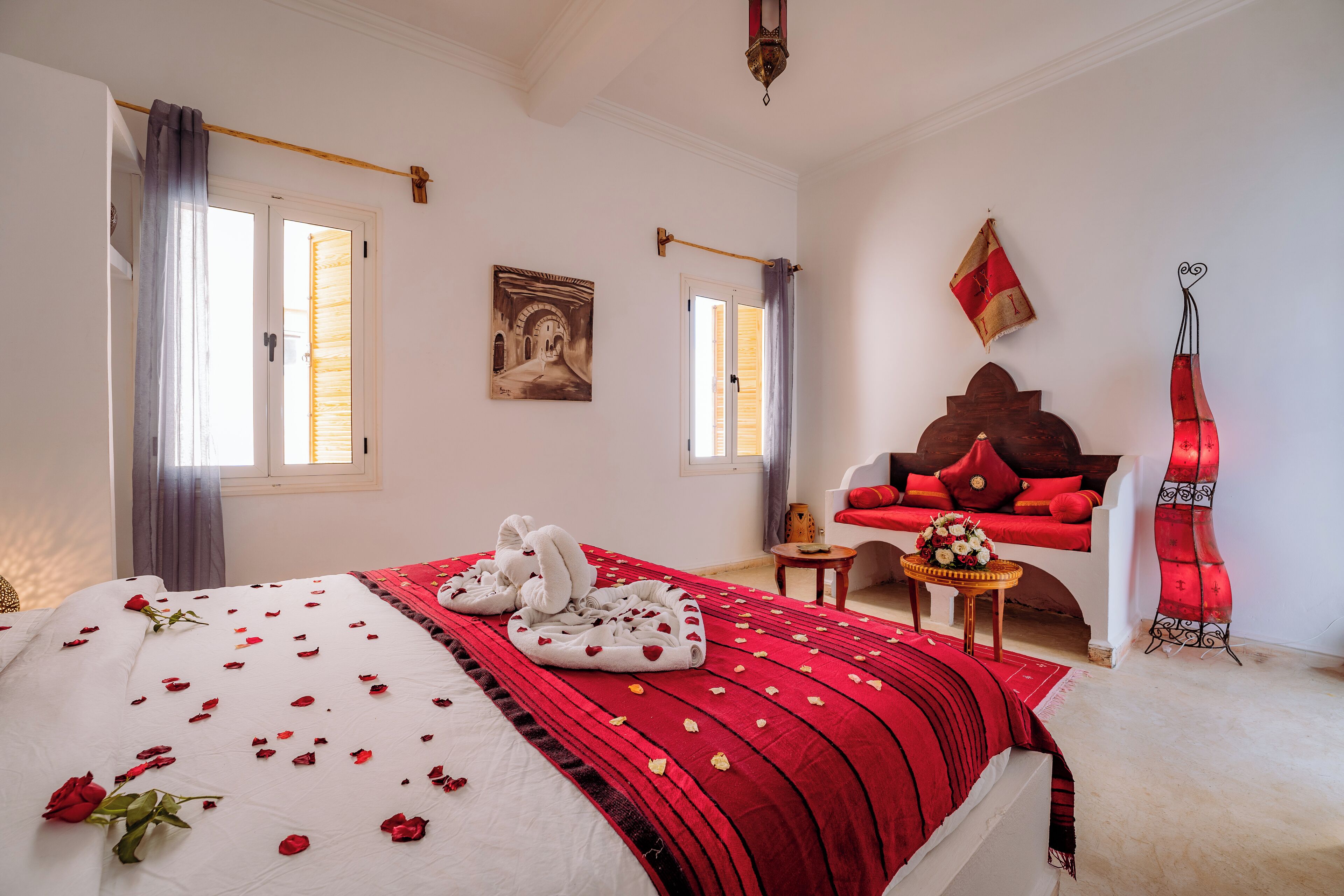A bedroom with a bed, a sofa, a small table with a vase, and a decorative item on the wall.
